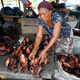 A woman prepares smoked fish for sale at a marketplace in Libreville, Gabon,